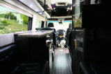 Spacious rv rental interior: A white dog rests on wood floors, framed by plush seats, a kitchen counter, and a scenic window view.