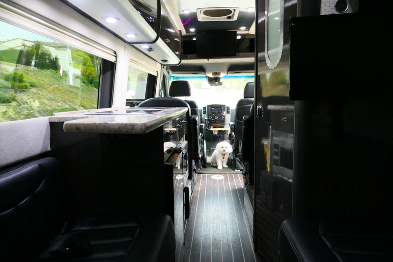  as a couple relaxes in chairs by a roadside.|Experience freedom with an RV rental! A woman on a rock admires majestic mountains beside a black Airstream.|Two young boys relax in custom bunk beds inside an RV rental — photo 11
