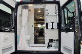 View from the rear of an RV rental: a compact interior features a bathroom with shower/toilet, and smart storage solutions.