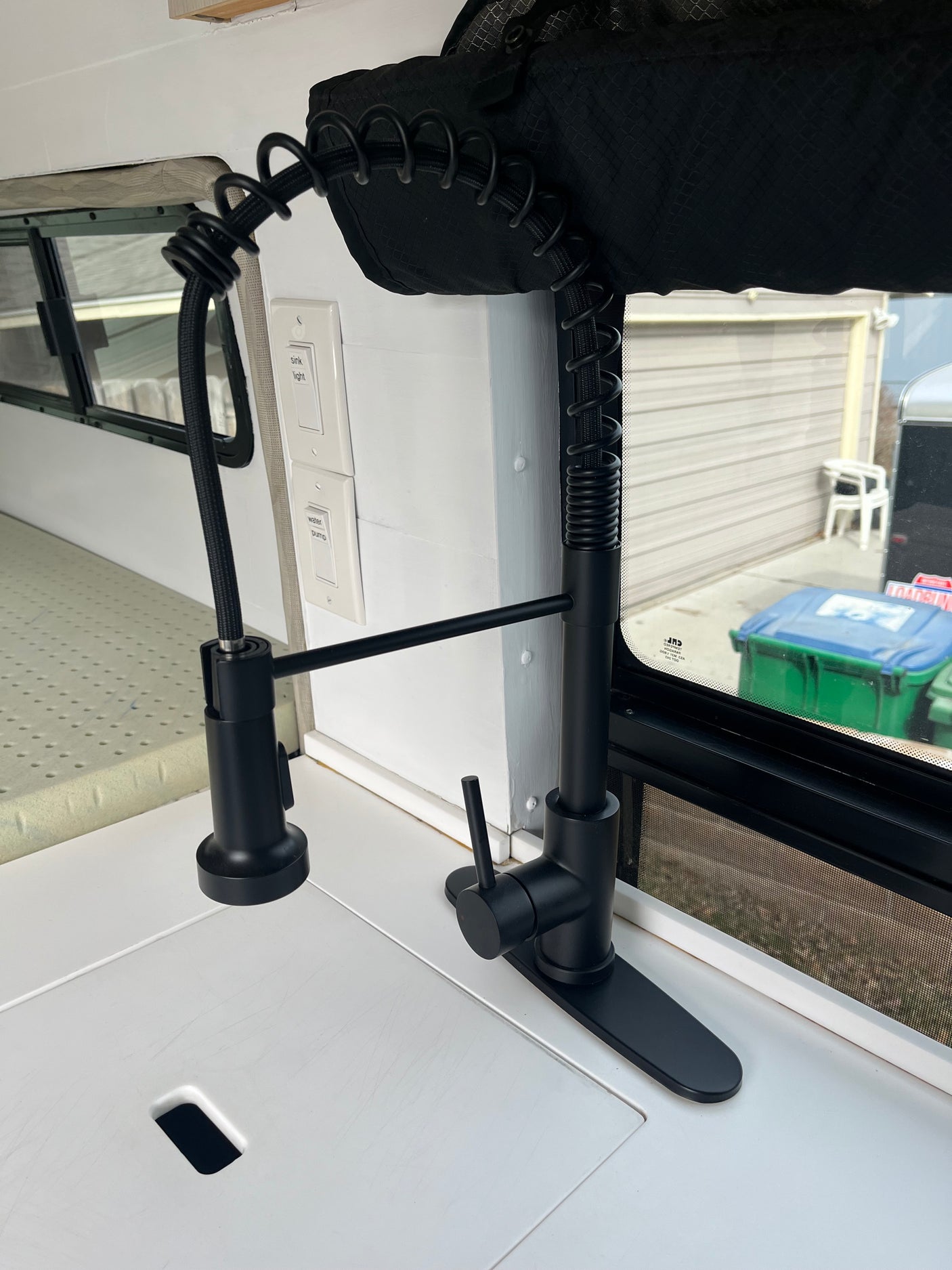 Black kitchen faucet, "sink light" & "water pump" switches in this compact RV rental kitchen. Perfect for camper use.