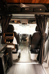 View of an RV rental camper van interior looking forward to the driver's area, showing practical storage and comforts.