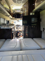 Inside a premium RV rental: sleek interior with a kitchen, TV, comfortable seating, and a dog relaxing.