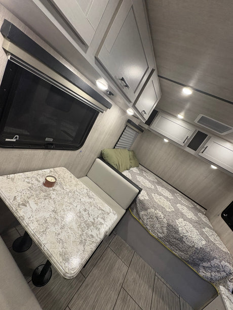 Cozy modern RV interior ready for your next rv rental adventure, featuring a dinette and bed area.