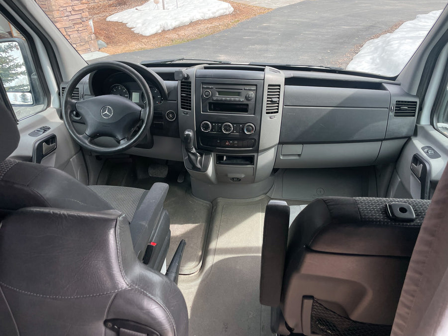 RV rental van interior: Driver's view with dashboard, steering wheel, and seating area. Ready for adventure.