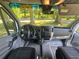 Driver's perspective inside an rv rental, showing the dashboard, steering wheel, and a 'VEHICLE HEIGHT 10FT' sticker.