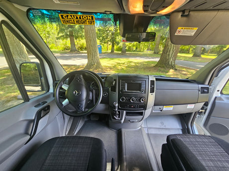 Driver's perspective inside an rv rental, showing the dashboard, steering wheel, and a 'VEHICLE HEIGHT 10FT' sticker.