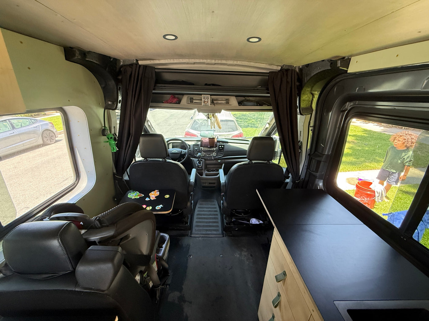 Interior of an RV rental van, showing the front cab, child seat, and custom living space with a kitchen counter. — photo 13