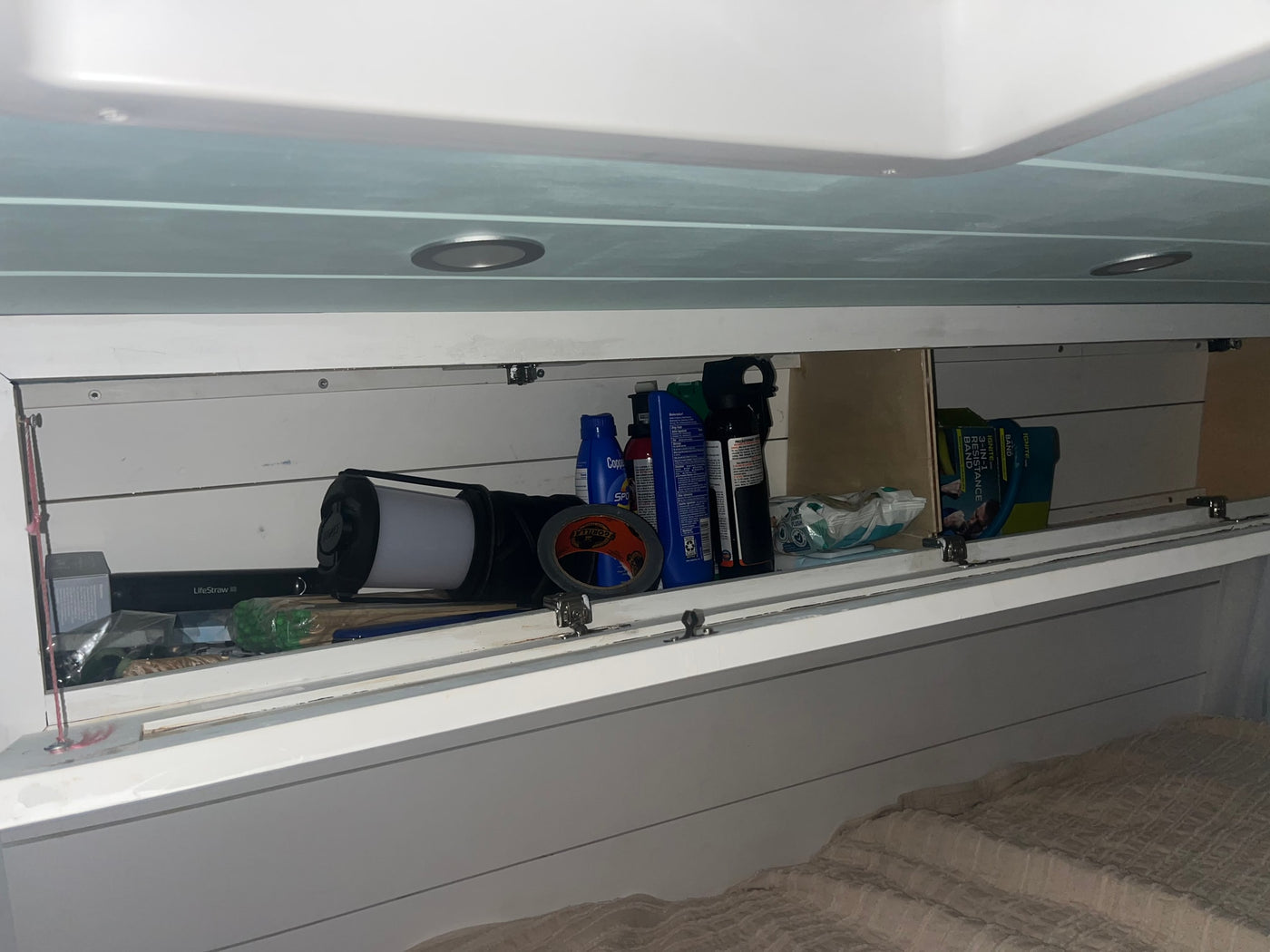 This RV rental's overhead cabinet is stocked with travel essentials like a LifeStraw, Gorilla tape, and resistance band. — photo 10