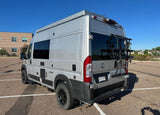 Silver Ram ProMaster camper van with a bike rack, perfect for travel & van life RV rental adventures.
