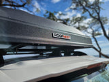 A textured, dark gray ROOFNEST rooftop cargo carrier is mounted on an RV rental vehicle, ready for outdoor adventure.