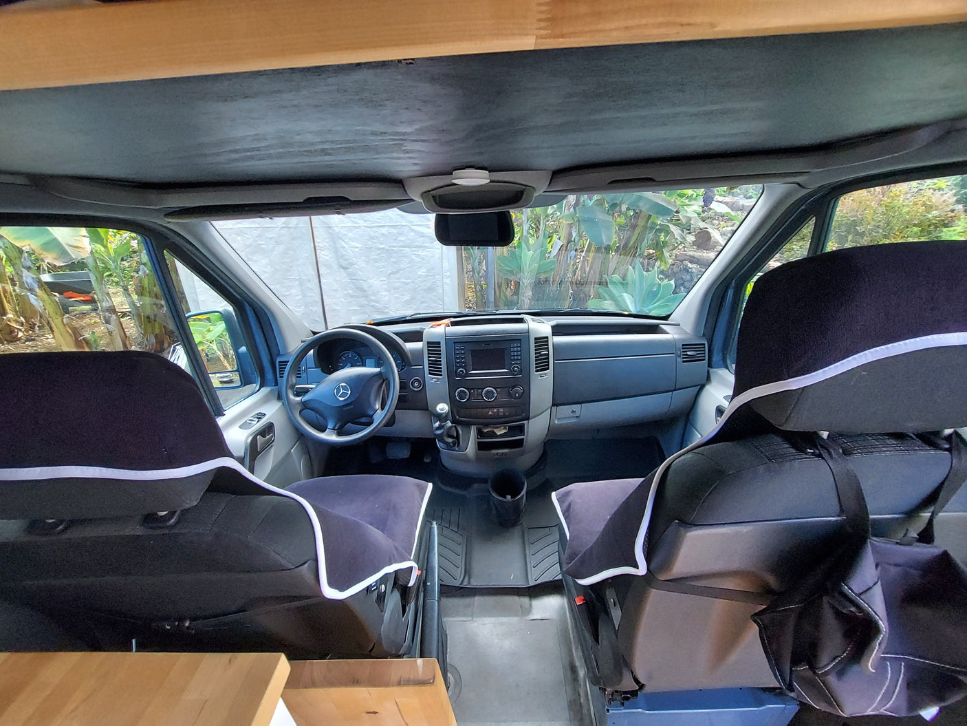 View inside an RV rental: driver's cabin with dashboard, steering wheel, and front seats.