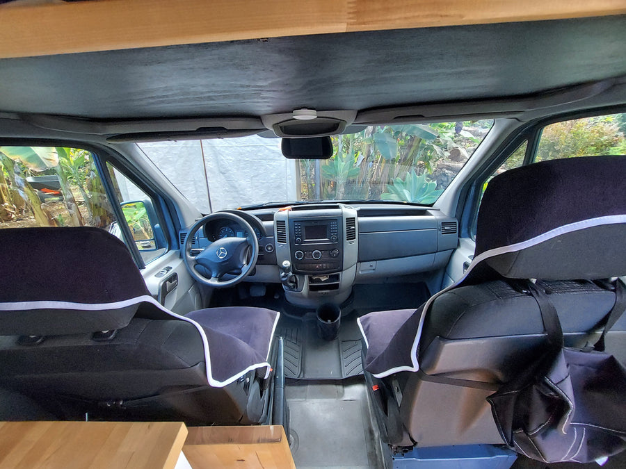 View inside an RV rental: driver's cabin with dashboard, steering wheel, and front seats.