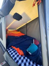 Inside an RV rental camping tent: a cozy bed with colorful blankets & pillows. Ready for adventure!