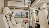 Inside an **RV rental**: Cream-colored seats, ladder to bunk, and cozy interior design perfect for your next road trip adventure.