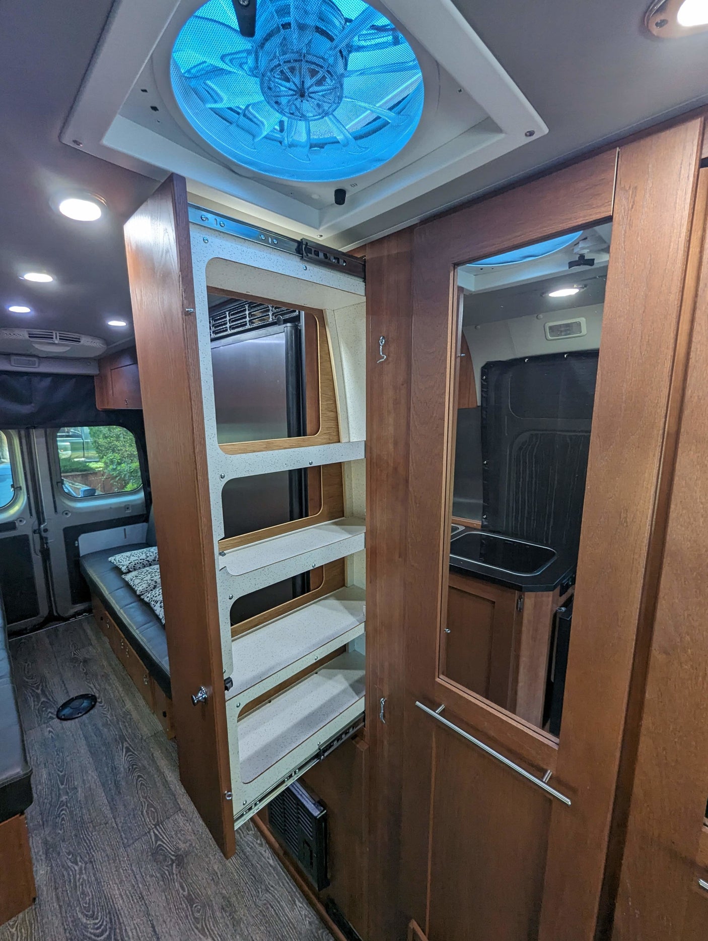 Explore this compact RV rental interior with a clever pull-out kitchen pantry, comfortable seating, and a modern design.