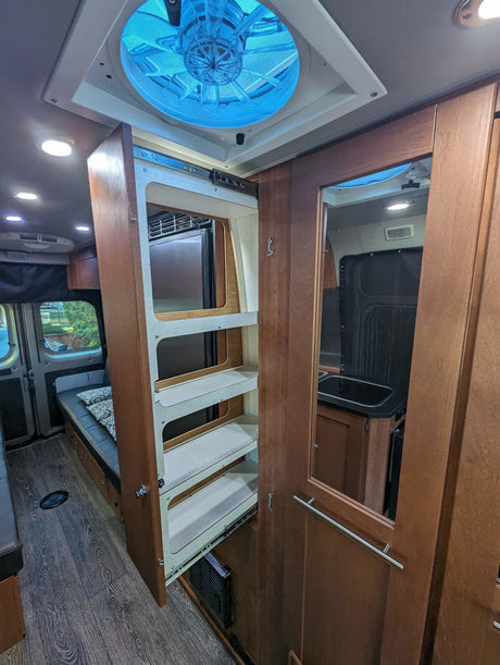 Explore this compact RV rental interior with a clever pull-out kitchen pantry, comfortable seating, and a modern design.