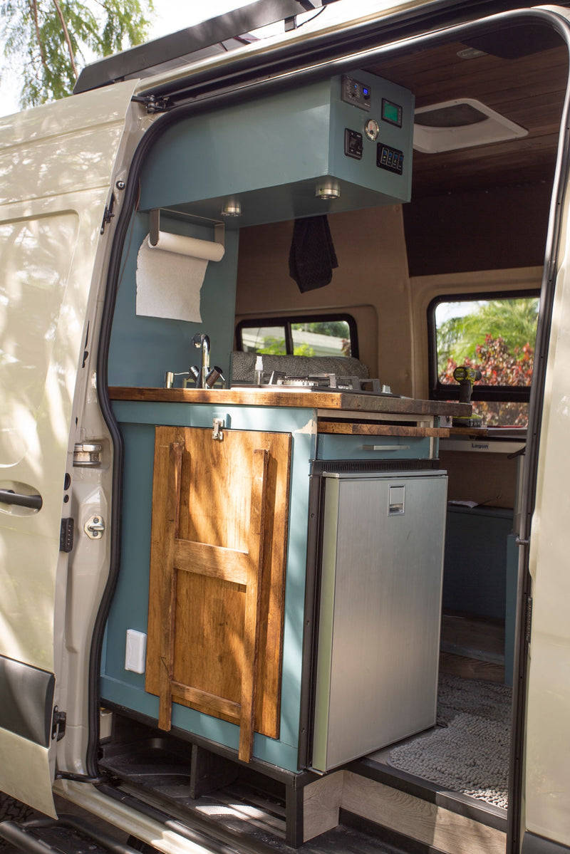 Inside an rv rental: a cozy camper van kitchen featuring a sink, stove, fridge, and custom cabinets. — photo 19