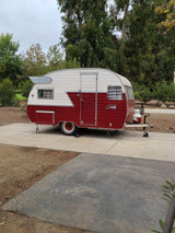 Retro red & white Shasta travel trailer, parked at a campsite, ready for your next RV rental adventure.