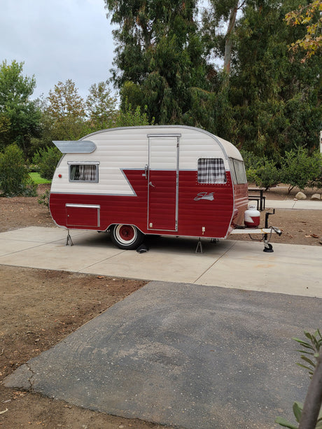 Retro red & white Shasta travel trailer, parked at a campsite, ready for your next RV rental adventure.