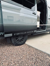 Gray Storyteller Overland van, open door showing interior, with off-road tires. Great RV rental for adventure.