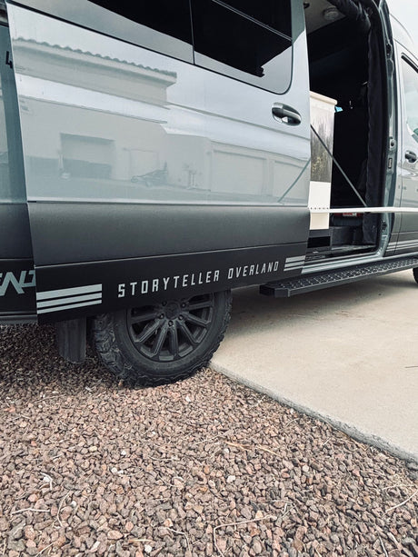 Gray Storyteller Overland van, open door showing interior, with off-road tires. Great RV rental for adventure.