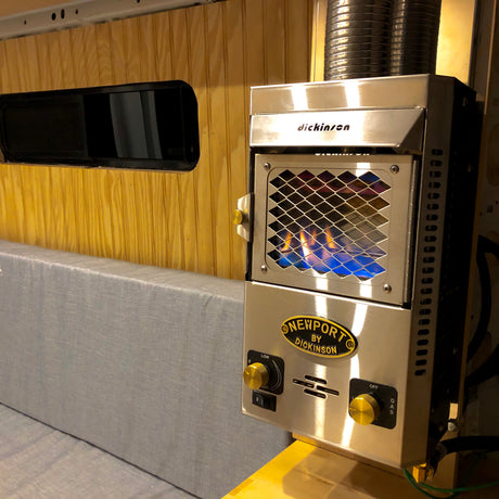 Dickinson Newport gas heater lit inside an rv rental, showing wood-paneled walls and a grey upholstered bench.