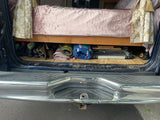 RV rental van interior: Organized under-bed storage for camping essentials like a grill and mats, seen from the rear.