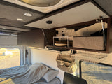 RV rental interior: Overhead storage with organizers, a compact dish shelf, and a comfortable bed for road trips.