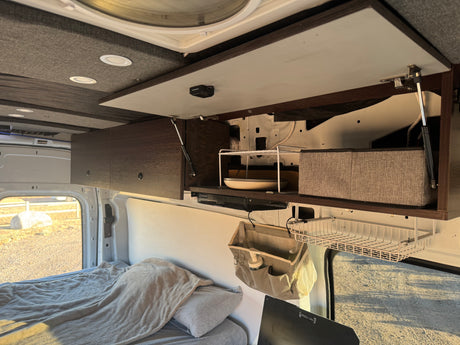 RV rental interior: Overhead storage with organizers, a compact dish shelf, and a comfortable bed for road trips.