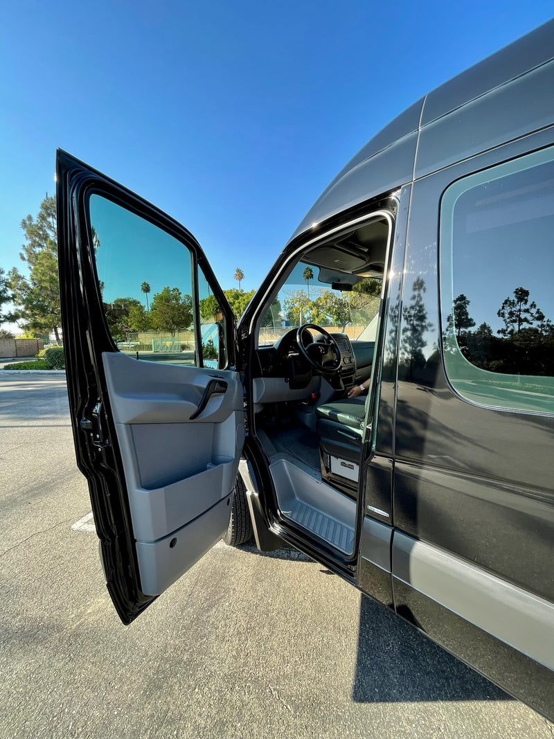 Spacious black van with its driver's door open, showcasing the interior. Perfect for your next rv rental adventure under a clear sky. — photo 8