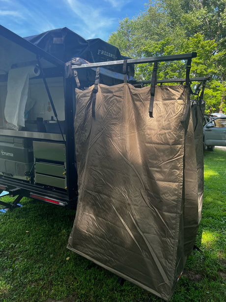 This overland trailer with an outdoor kitchen, shower tent, and rooftop tent, ideal for an RV rental adventure.