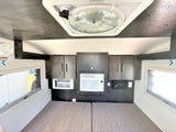 Inside an RV rental: a camper bedroom with mattresses, overhead storage, dual AC units, and ceiling fan.