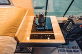 RV rental: Modern camper interior shows a compact kitchen with induction cooktop & kettle, next to a cozy bed. Functional space.
