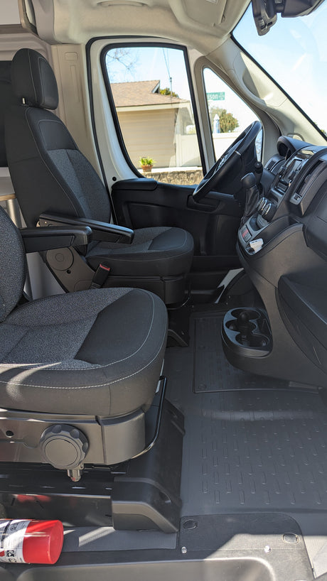 RV rental van's front cabin. Features swiveling seats, dashboard, cup holders, and a fire extinguisher for safety.