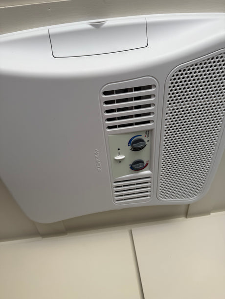 White Dometic RV rental air conditioner on ceiling with control panel, showing fan, temperature, and optional heat.