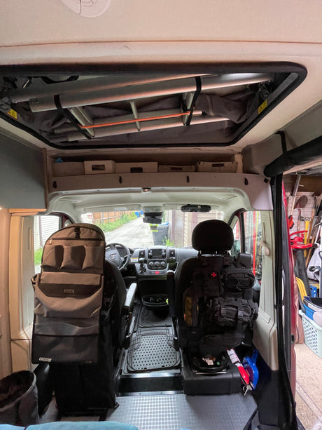 RV rental interior: A camper van's organized front cabin with seat organizers and overhead storage for travel essentials.