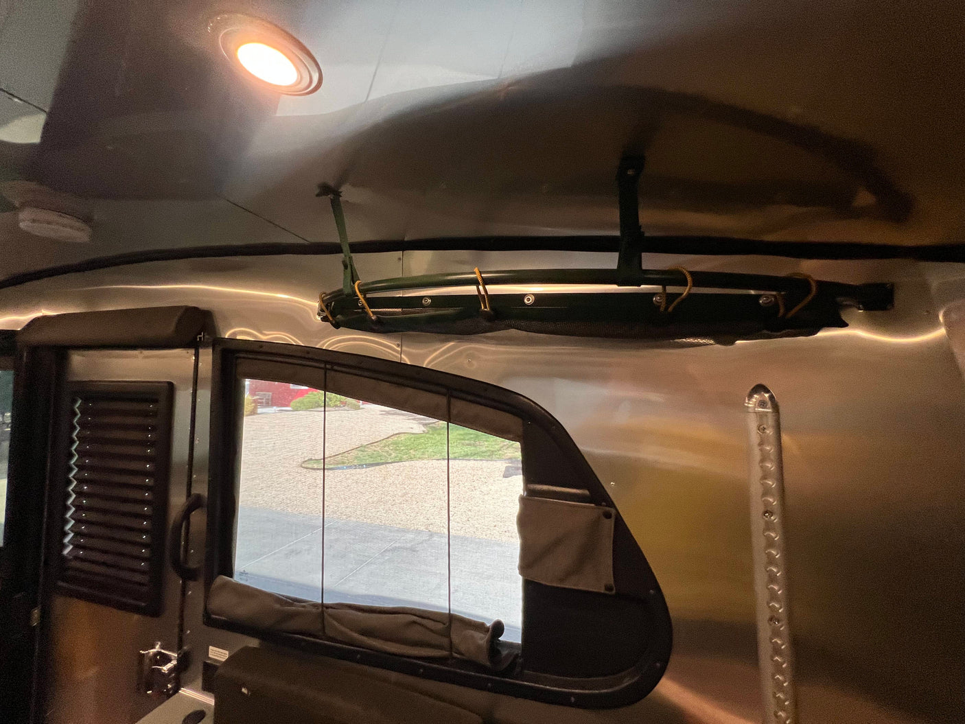 Bright ceiling light illuminates the polished interior of this RV rental, featuring overhead storage, a window, and durable walls.