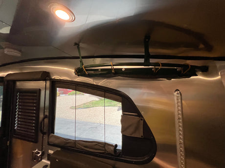 Bright ceiling light illuminates the polished interior of this RV rental, featuring overhead storage, a window, and durable walls.