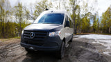 Rugged Mercedes Sprinter RV rental camper van on a muddy trail with melting snow, ready for off-road adventures.