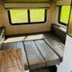 RV rental's adaptable interior: a clean dinette setup that converts to a bed, with windows showing green scenery.