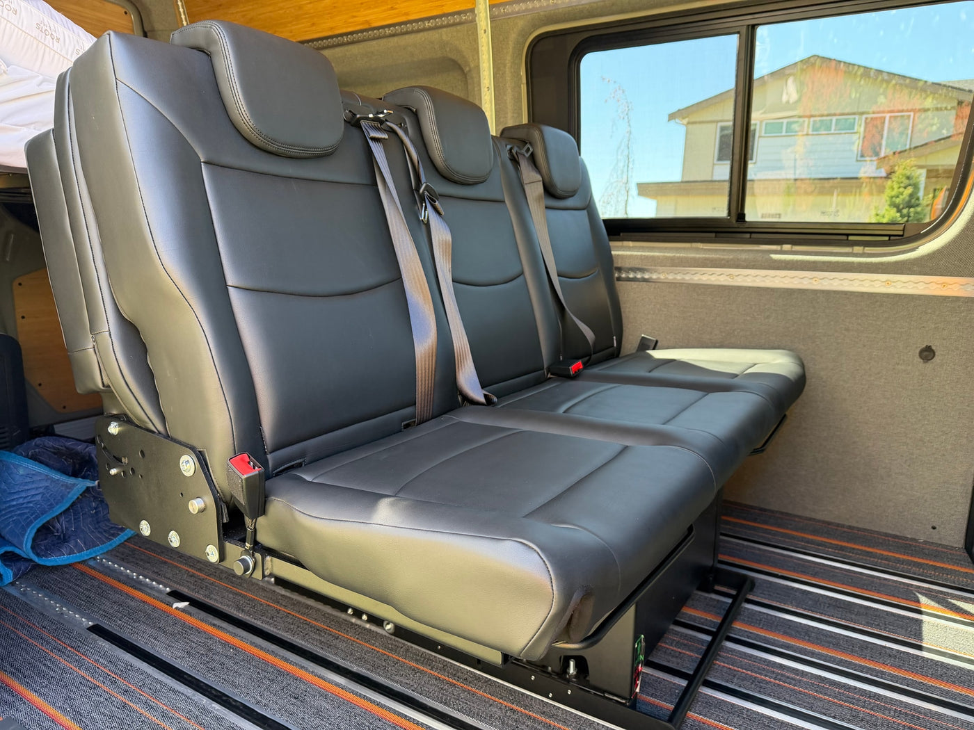 RV rental: Flexible three-person black bench seat with individual seatbelts on adjustable floor rails in a spacious van. — photo 7