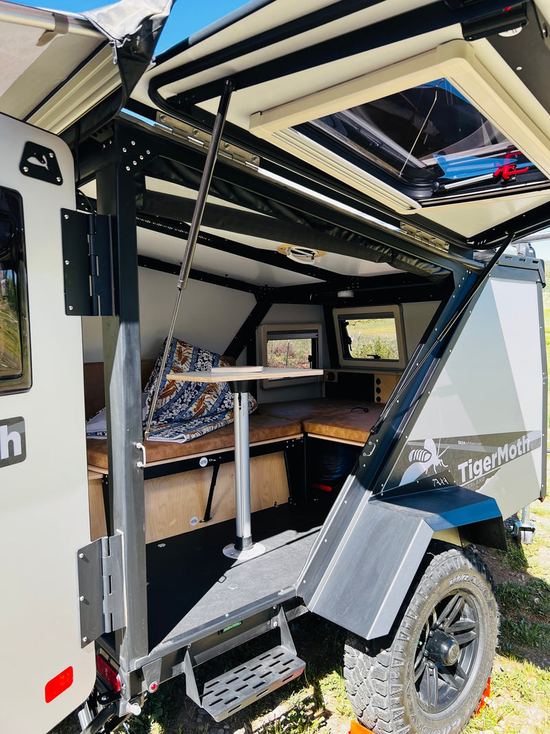 Open Taxa TigerMoth off-grid camper for rv rental. Reveals compact interior with table, seating, and rugged off-road exterior. — photo 12