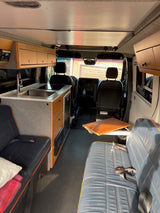 Compact rv rental interior with kitchen, lounge seating, and overhead cabinets for a comfortable mobile lifestyle.