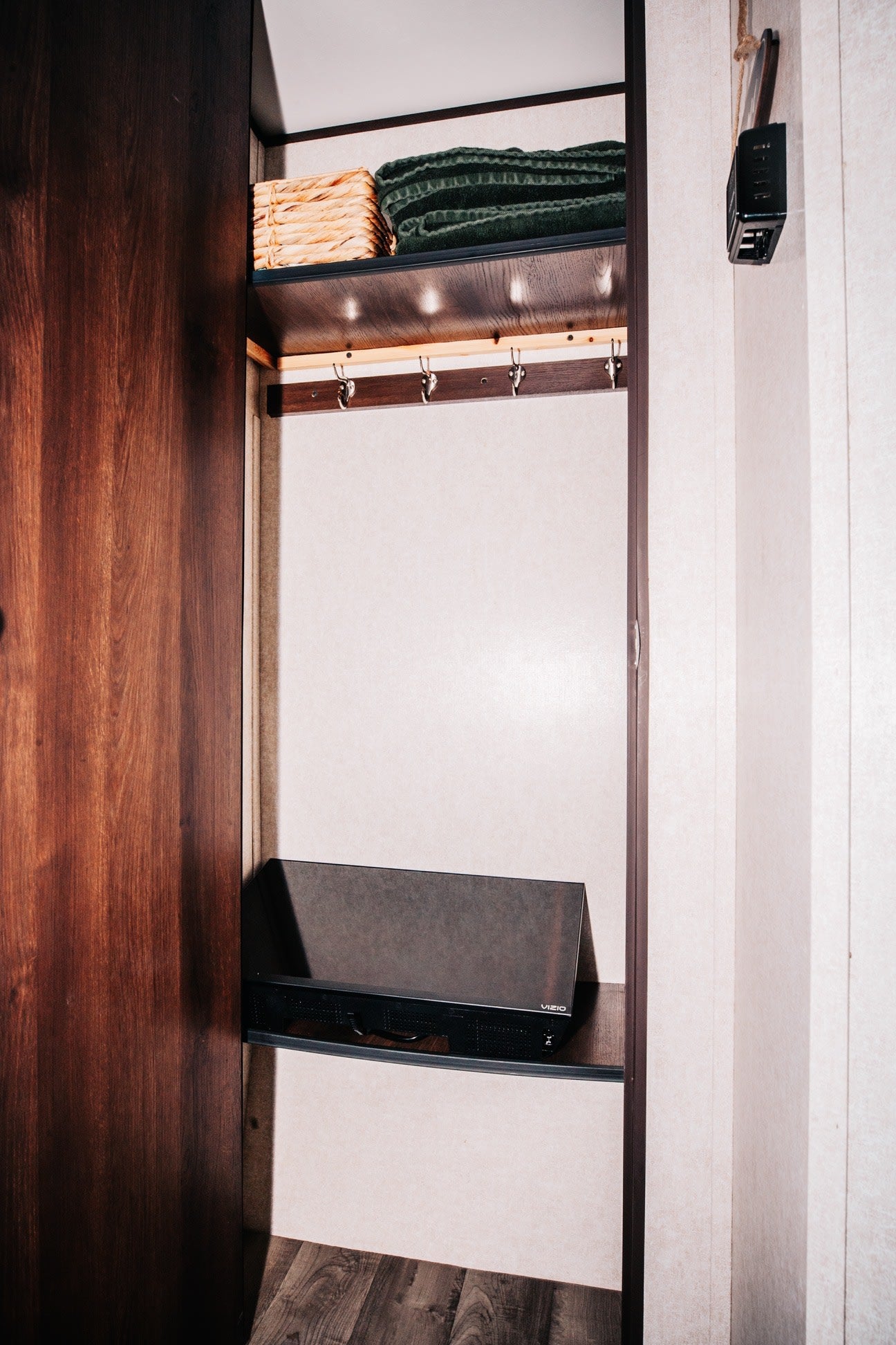 RV rental interior: A well-organized closet with shelves, towels, baskets, coat hooks, and a VIZIO entertainment unit.