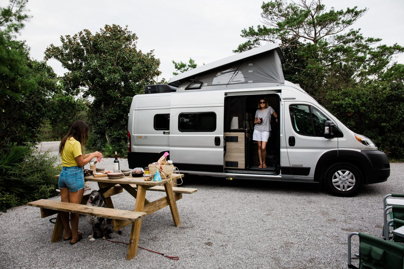  with open side door and natural surroundings.|White Winnebago Ram ProMaster camper van RV rental with open side door revealing interior — photo 3