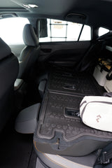 Car interior with folded rear seats & durable cargo mats, ready for an RV rental road trip. Cooler & gear stored securely.