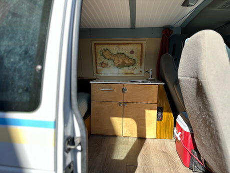 Explore with this rv rental's custom van interior featuring a kitchenette, Maui map, bed, and smart storage for road trips.