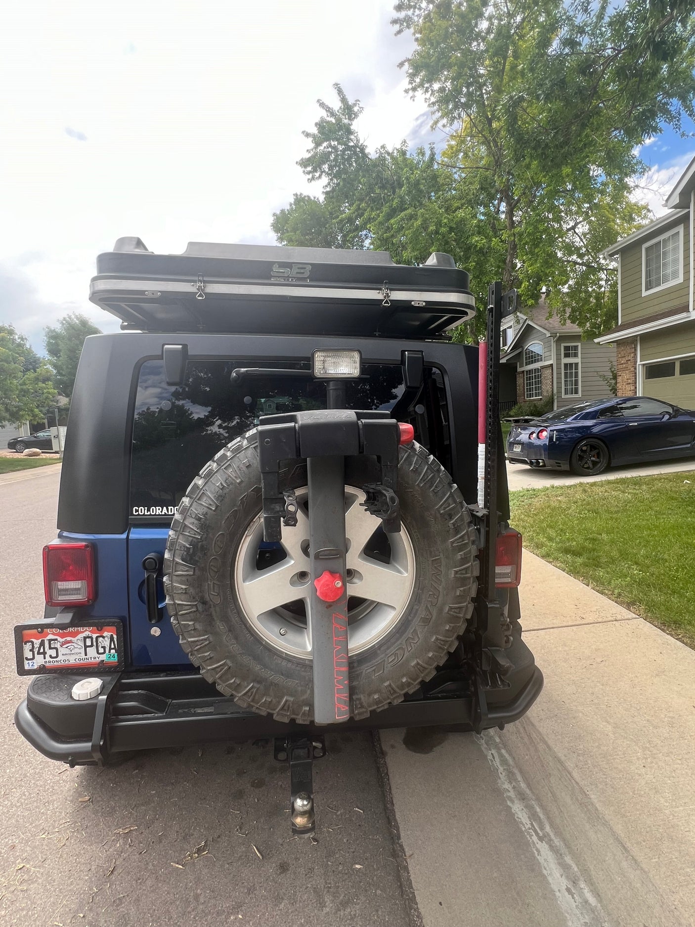 Rear view of a blue Jeep Wrangler, featuring a rooftop tent and bike rack, prepared for outdoor adventures. Great for an RV rental trip!