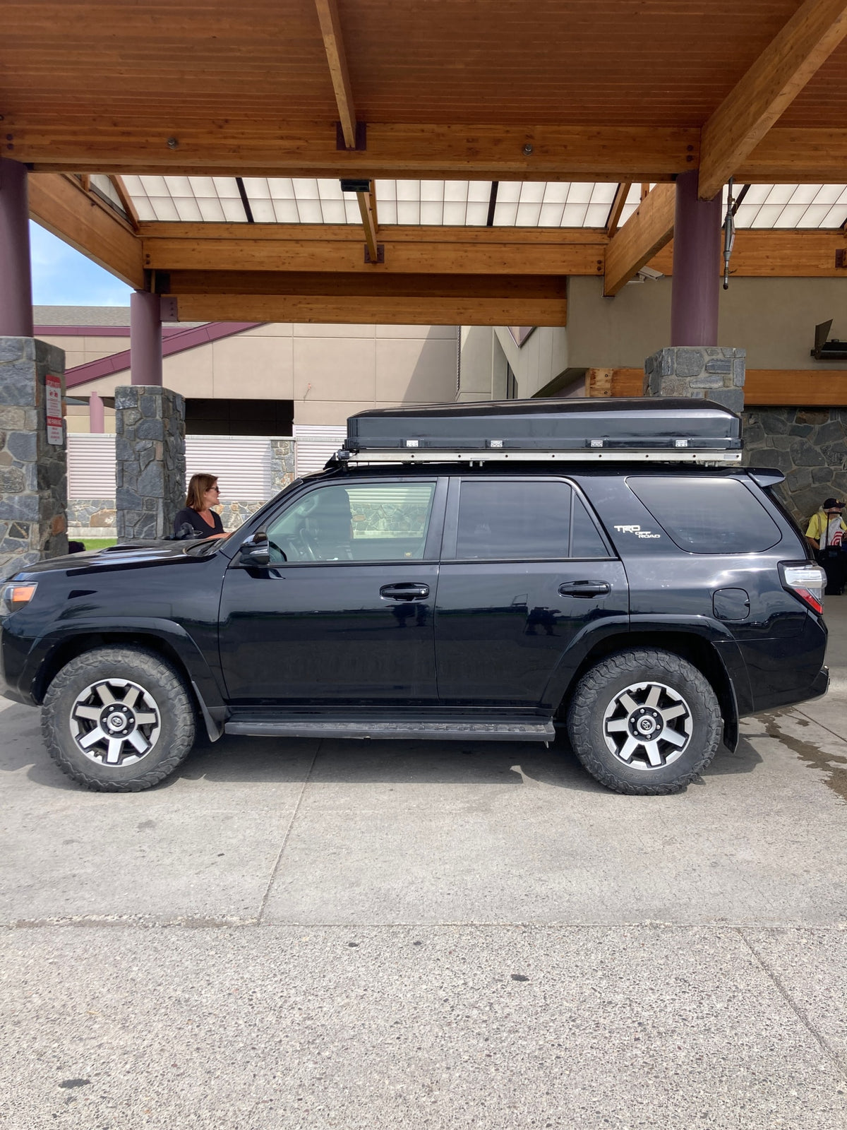A black Toyota 4Runner SUV, equipped with a rooftop tent for an RV rental adventure, parked beneath a rustic wooden structure. — photo 17