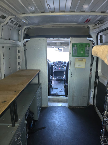 Cargo van interior with a workbench, storage, and eye wash station. A practical mobile workspace, different from an rv rental.